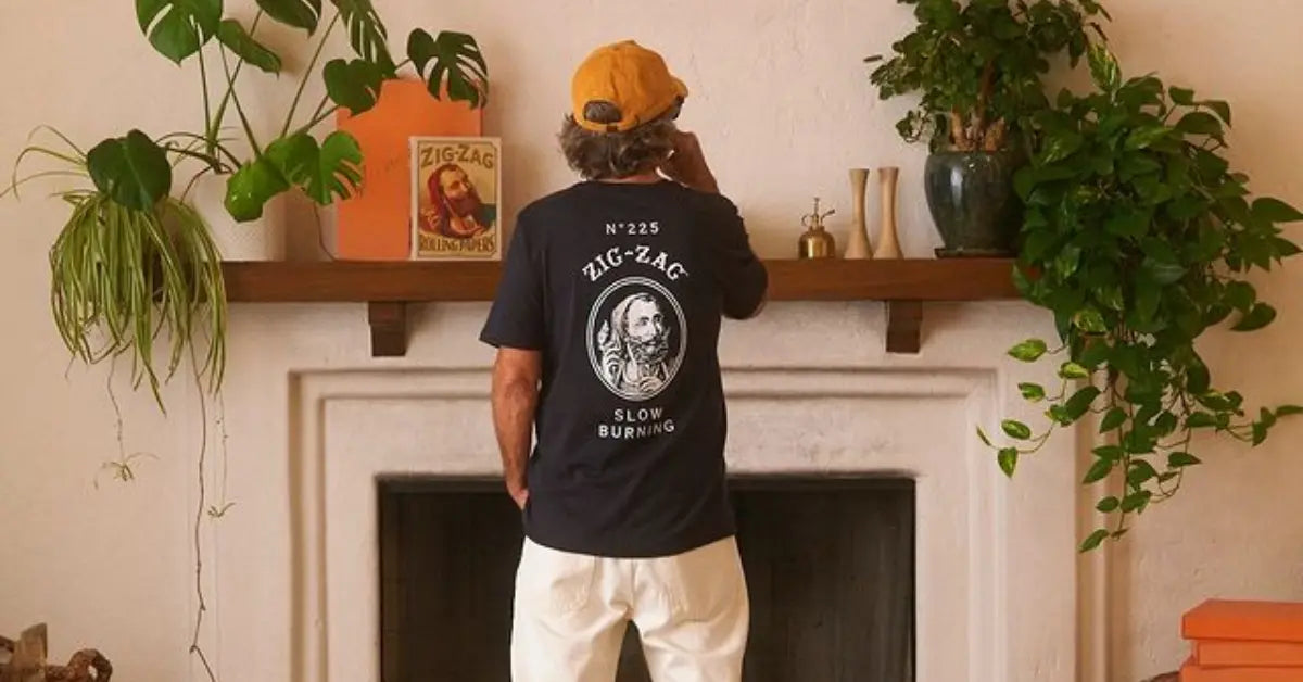 a Zig-Zag T-shirt with a printed design, standing by a shelf with plants