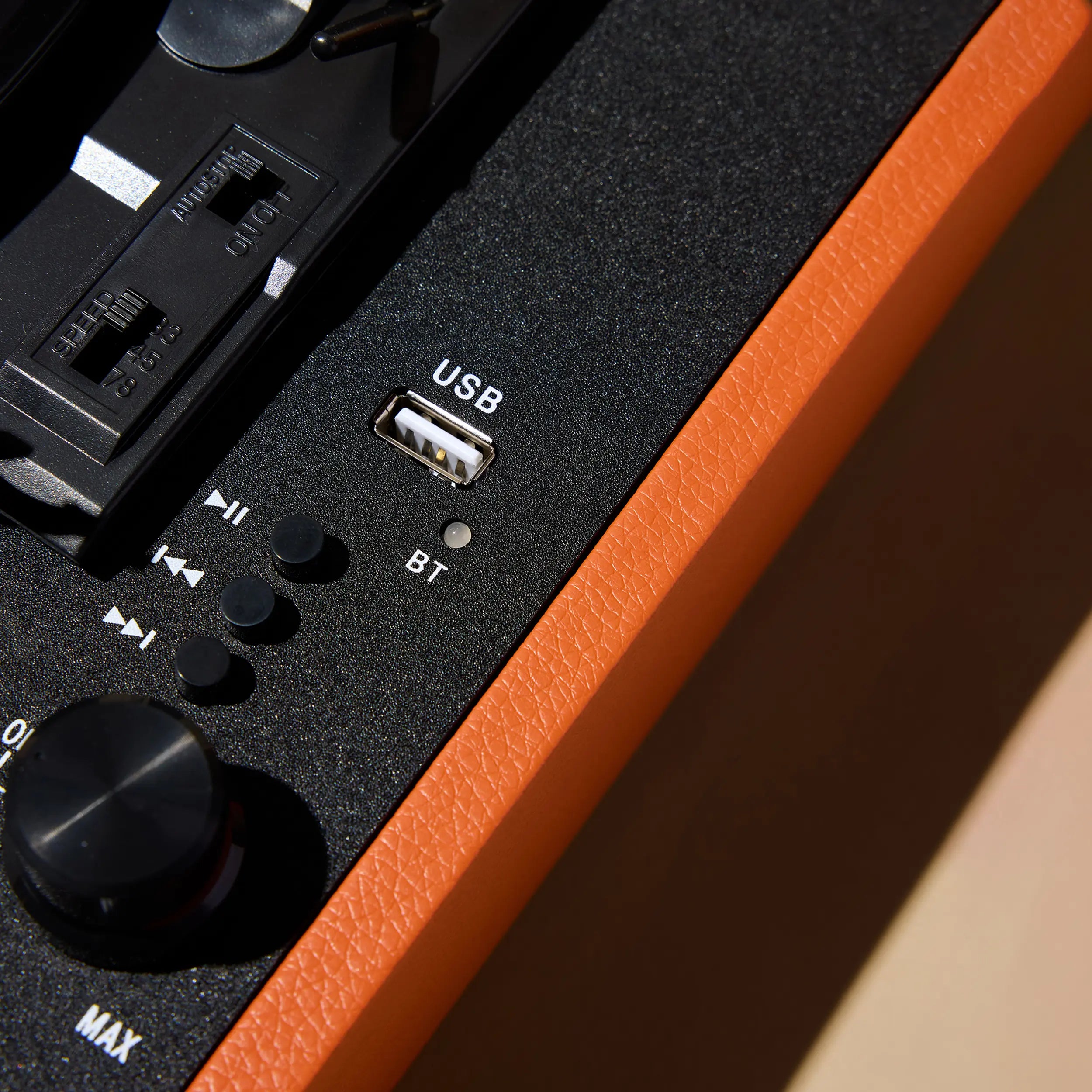 Zig Zag record player with orange leatherette finish featuring USB port, Bluetooth pairing button, volume knob, and playback controls.
