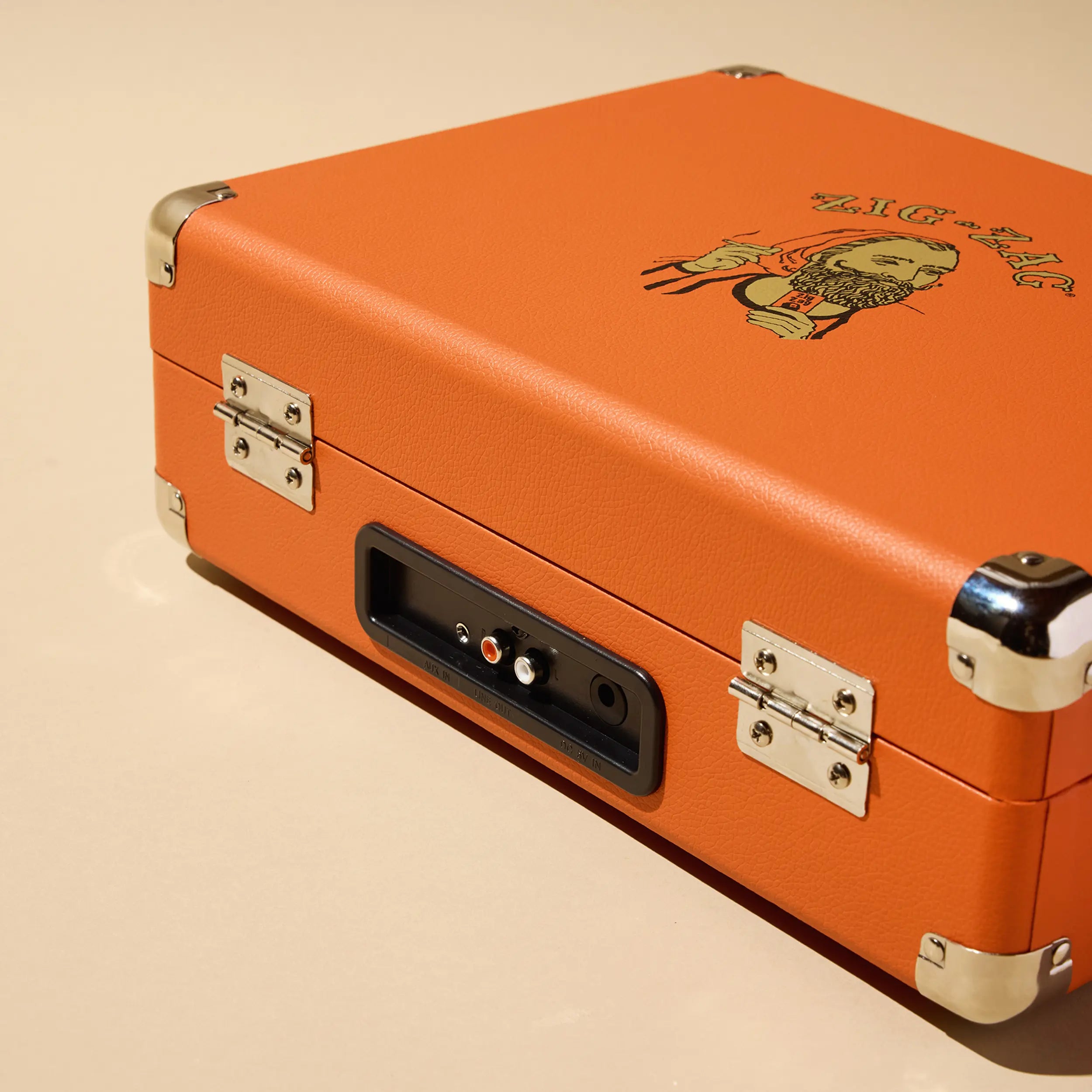 Orange Zig Zag record player with vintage logo and rear panel showing RCA outputs, aux port, and power connection.