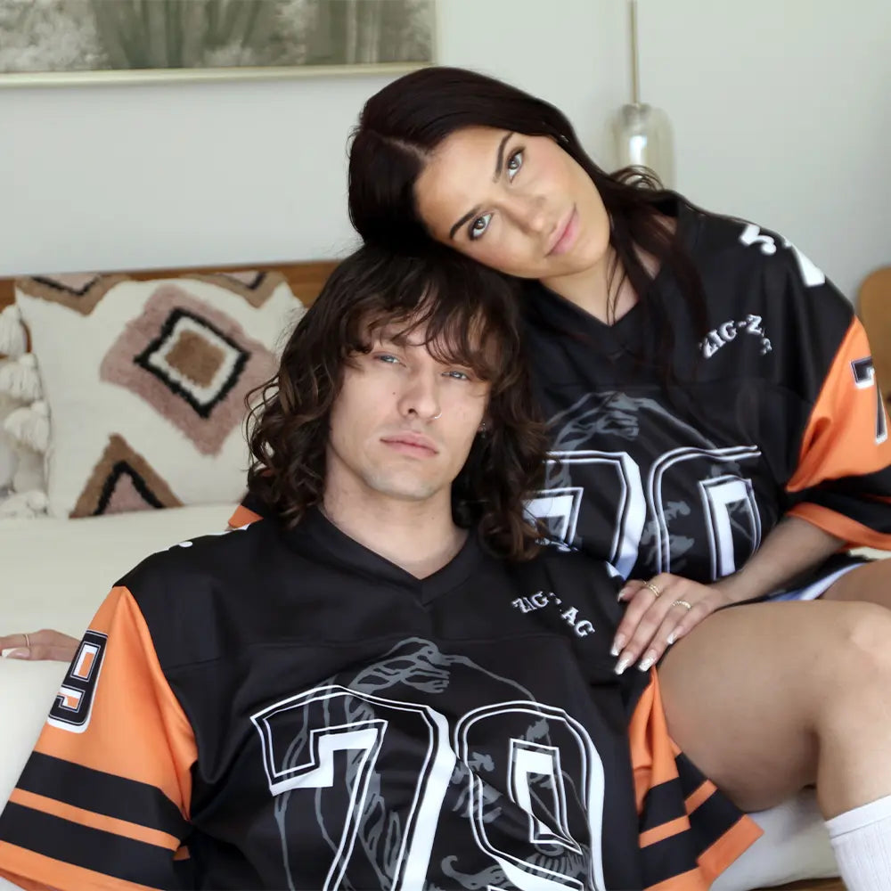 Zig Zag jersey featuring bold number 79 and orange-striped sleeves worn by two people lounging casually in a modern bedroom.