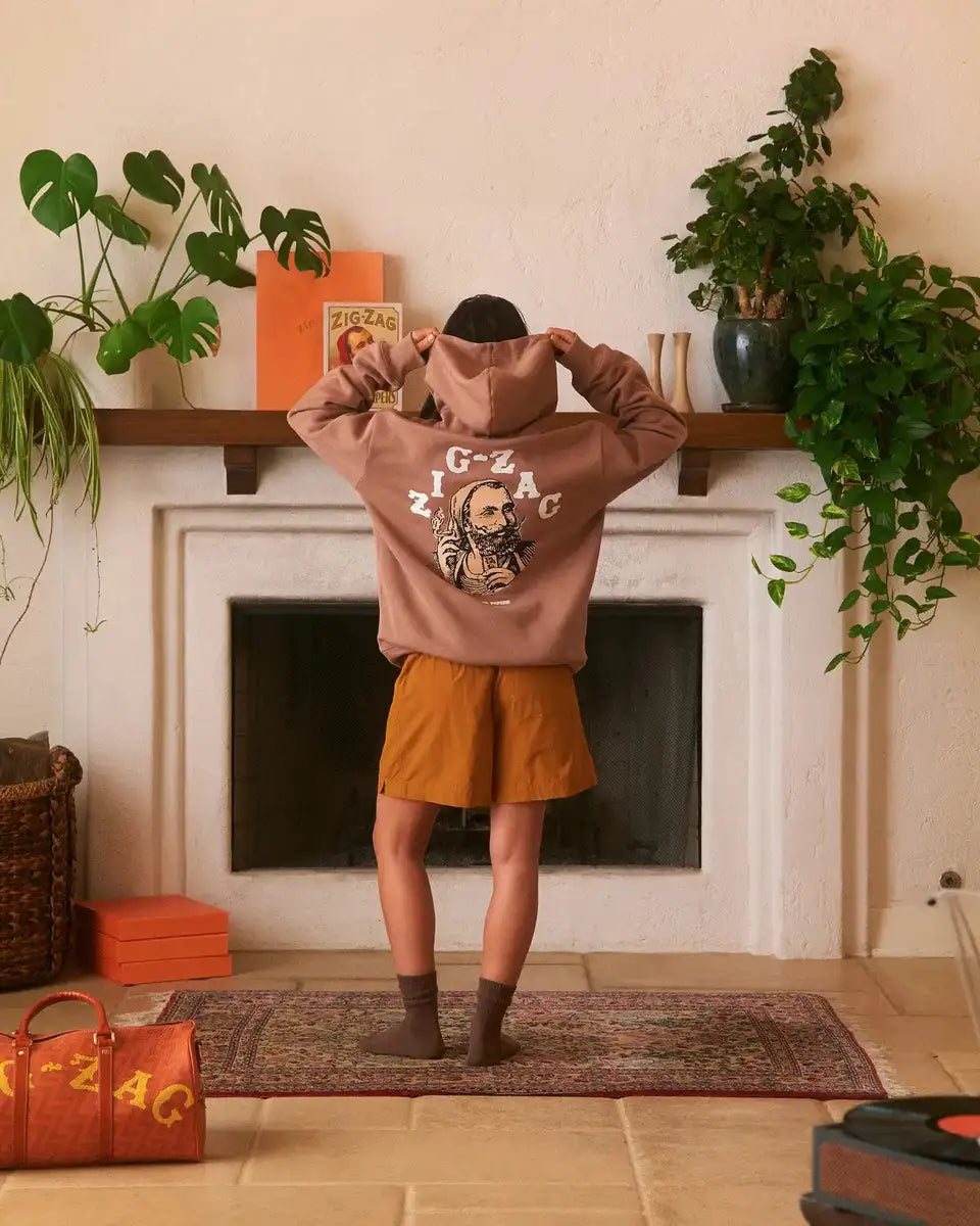 Zig-Zag hoodie with back graphic worn by a person in a cozy room with plants and branded decor.