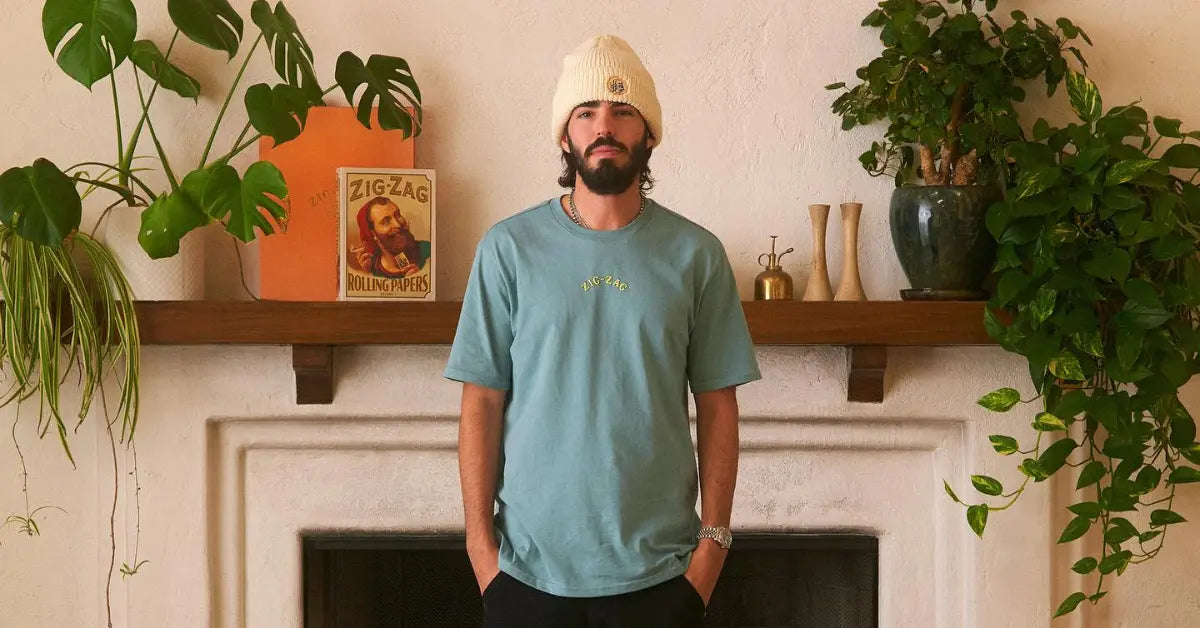Zig-Zag logo t-shirt in teal styled with a cream beanie, modeled in a living room with plants and decor.